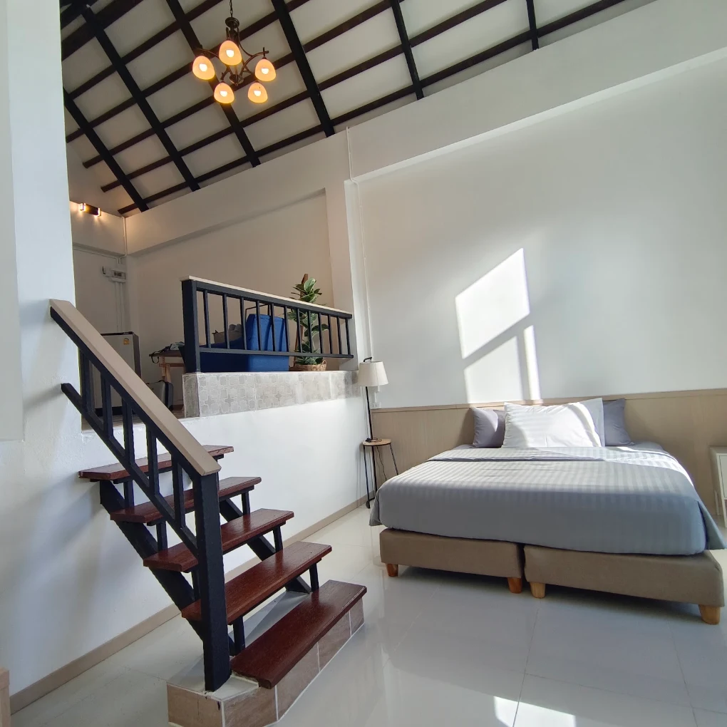 Small room loft with a queen bed, a wooden staircase to the mezzanine landing, and a wagon-wheel chandelier.